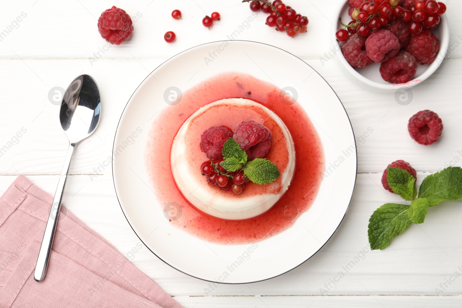 Delicious panna cotta with berries, sauce and mint on white wooden table, flat lay Photo of Delicious panna cotta with berries, sauce and mint on white wooden table, flat lay