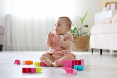 Photo of Cute little baby playing with toys on floor at home