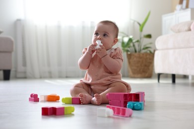 Photo of Cute little baby playing with toys on floor at home