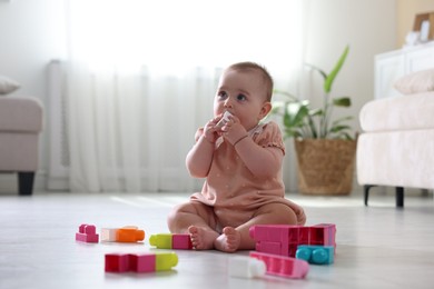 Photo of Cute little baby playing with toys on floor at home