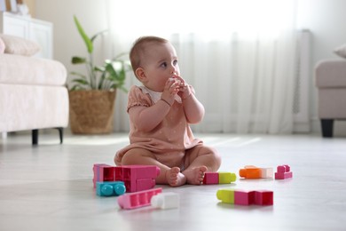 Photo of Cute little baby playing with toys on floor at home