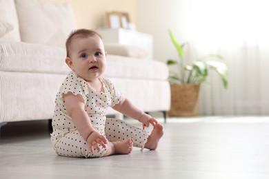 Photo of Cute little baby sitting on floor at home, space for text