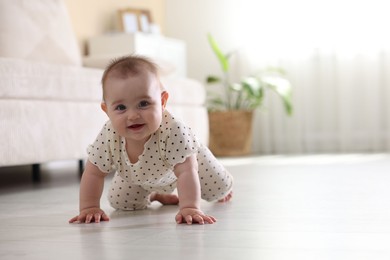 Photo of Cute little baby crawling on floor at home, space for text