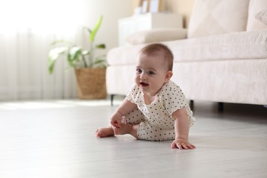 Photo of Cute little baby crawling on floor at home, space for text
