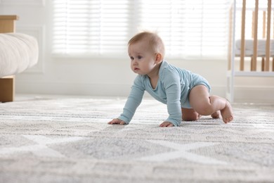 Photo of Cute little baby crawling on floor at home, space for text