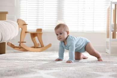 Photo of Cute little baby crawling on floor at home, space for text