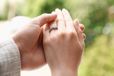 Photo of Making proposal. Woman with engagement ring and her fiance holding hands outdoors, closeup