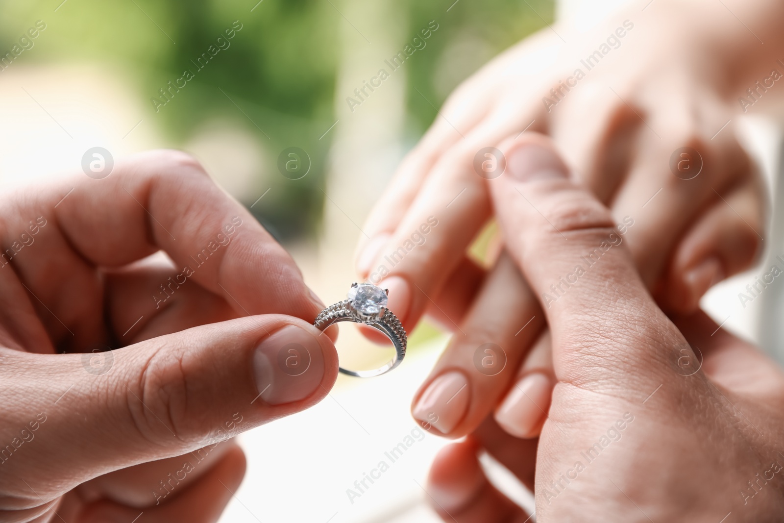 Making proposal. Man putting engagement ring on his girlfriend's finger outdoors, closeup Photo of Making proposal. Man putting engagement ring on his girlfriend's finger outdoors, closeup