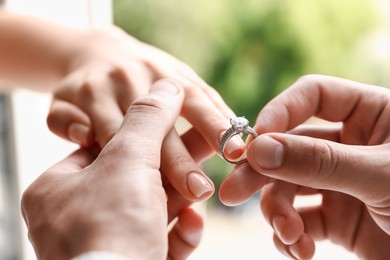 Photo of Making proposal. Man putting engagement ring on his girlfriend's finger outdoors, closeup