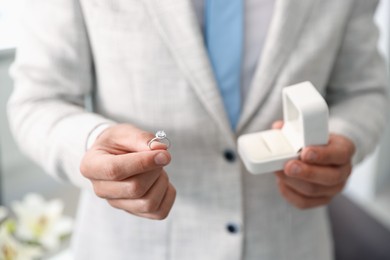 Photo of Making proposal. Man with engagement ring indoors, closeup