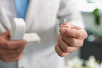 Photo of Making proposal. Man with engagement ring indoors, closeup