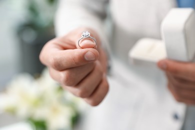 Photo of Making proposal. Man with engagement ring indoors, closeup