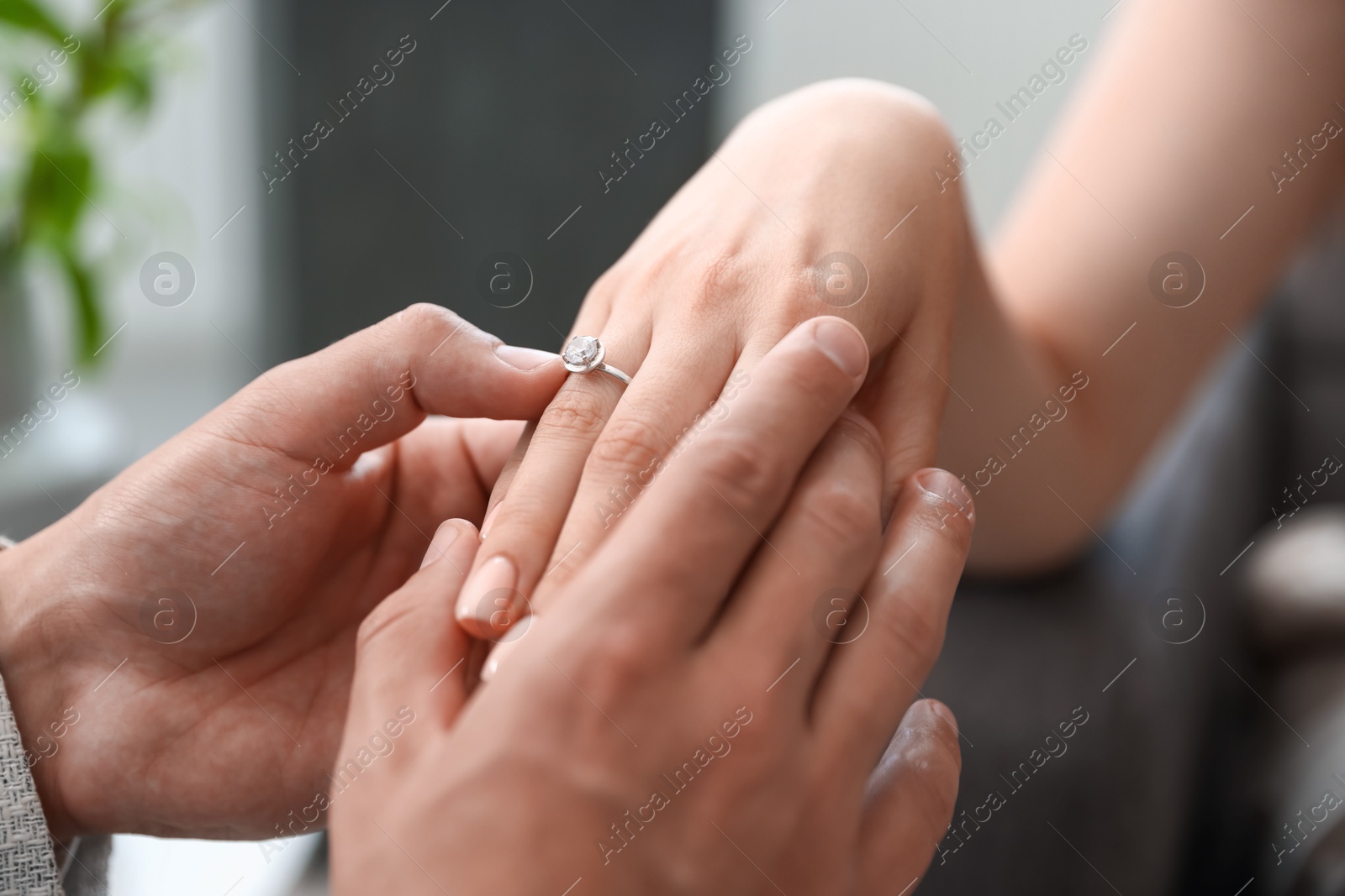 Making proposal. Man putting engagement ring on his girlfriend's finger indoors, closeup Photo of Making proposal. Man putting engagement ring on his girlfriend's finger indoors, closeup