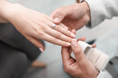 Photo of Making proposal. Man putting engagement ring on his girlfriend's finger indoors, above view