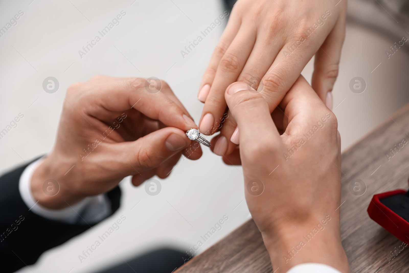 Making proposal. Man putting engagement ring on his girlfriend's finger indoors, closeup Photo of Making proposal. Man putting engagement ring on his girlfriend's finger indoors, closeup