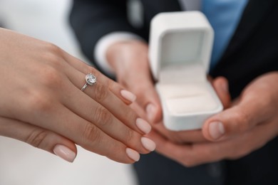 Photo of Making proposal. Woman with engagement ring and her fiance indoors, closeup