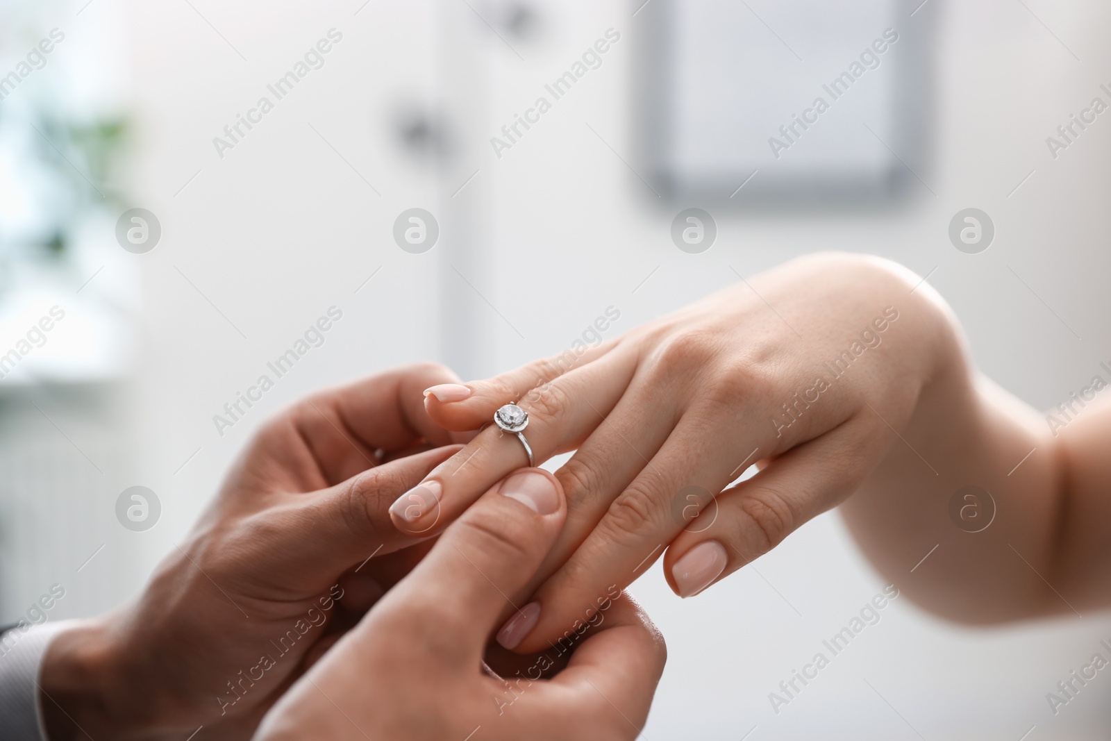 Making proposal. Man putting engagement ring on his girlfriend's finger indoors, closeup Photo of Making proposal. Man putting engagement ring on his girlfriend's finger indoors, closeup