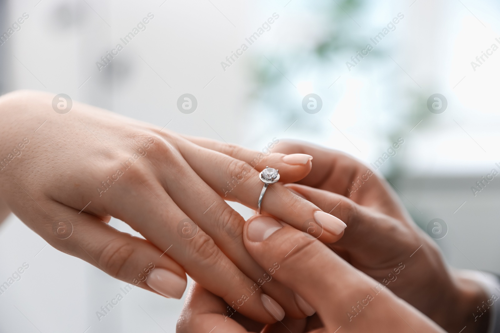 Making proposal. Man putting engagement ring on his girlfriend's finger indoors, closeup Photo of Making proposal. Man putting engagement ring on his girlfriend's finger indoors, closeup