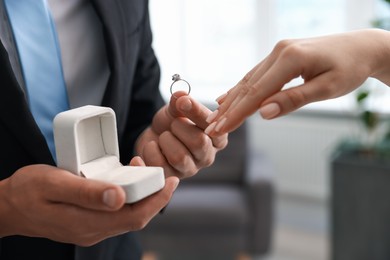 Photo of Man with engagement ring making marriage proposal to his girlfriend indoors, closeup