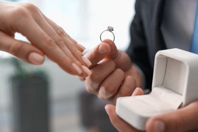 Photo of Man with engagement ring making marriage proposal to his girlfriend indoors, closeup