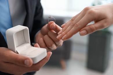 Photo of Man with engagement ring making marriage proposal to his girlfriend indoors, closeup