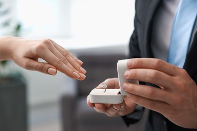Photo of Man with engagement ring making marriage proposal to his girlfriend indoors, closeup