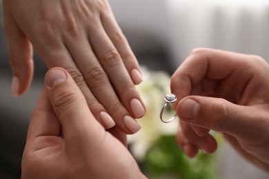 Photo of Man with engagement ring making marriage proposal to his girlfriend indoors, closeup