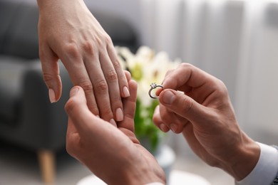 Photo of Man with engagement ring making marriage proposal to his girlfriend indoors, closeup