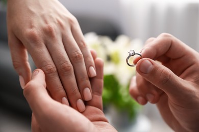 Photo of Man with engagement ring making marriage proposal to his girlfriend indoors, closeup