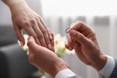 Photo of Man with engagement ring making marriage proposal to his girlfriend indoors, closeup