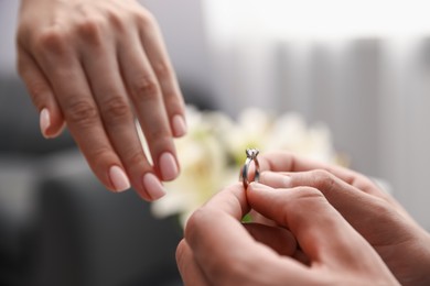 Photo of Man with engagement ring making marriage proposal to his girlfriend indoors, closeup
