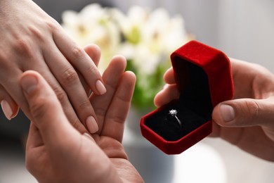 Photo of Man with engagement ring making marriage proposal to his girlfriend indoors, closeup