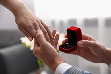 Photo of Man with engagement ring making marriage proposal to his girlfriend indoors, closeup