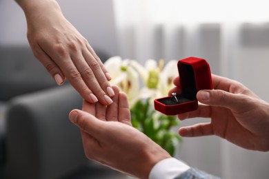 Photo of Man with engagement ring making marriage proposal to his girlfriend indoors, closeup