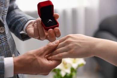 Photo of Man with engagement ring making marriage proposal to his girlfriend indoors, closeup
