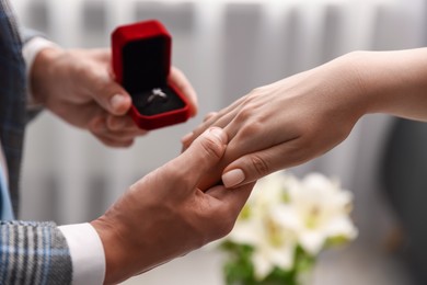 Photo of Man with engagement ring making marriage proposal to his girlfriend indoors, closeup