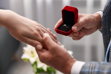 Photo of Man with engagement ring making marriage proposal to his girlfriend indoors, closeup