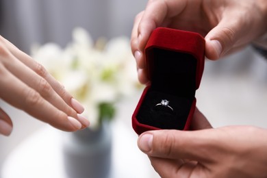 Photo of Man with engagement ring making marriage proposal to his girlfriend indoors, closeup