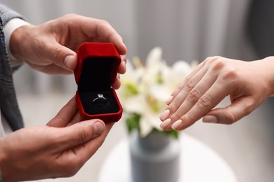Photo of Man with engagement ring making marriage proposal to his girlfriend indoors, closeup