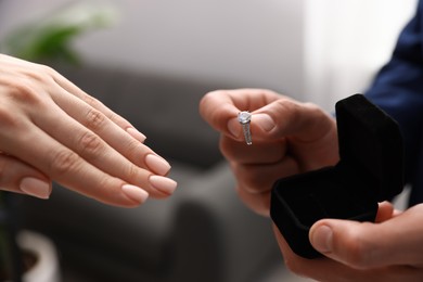 Photo of Man with engagement ring making marriage proposal to his girlfriend indoors, closeup