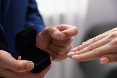 Photo of Man with engagement ring making marriage proposal to his girlfriend indoors, closeup