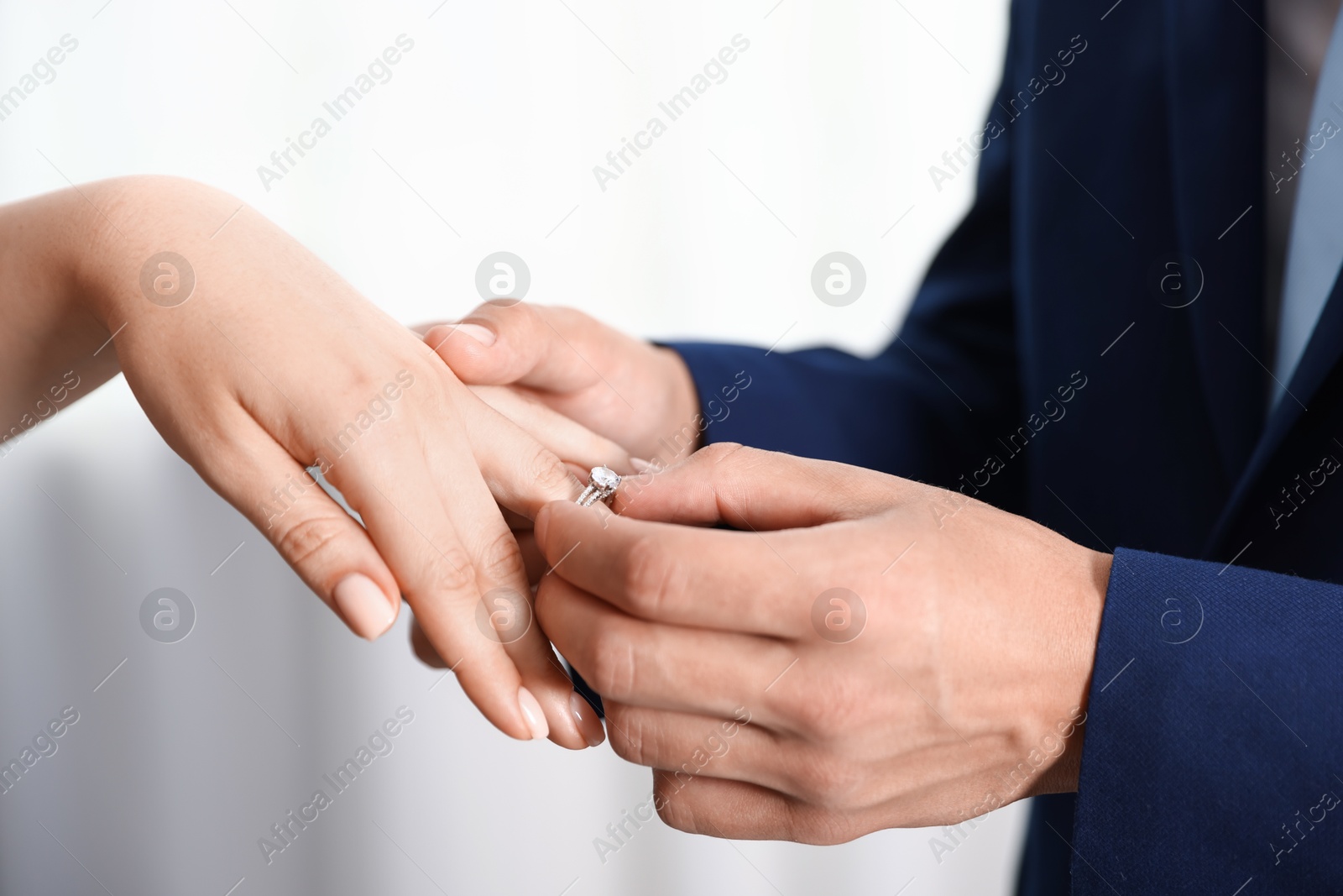 Making proposal. Man putting engagement ring on his girlfriend's finger indoors, closeup Photo of Making proposal. Man putting engagement ring on his girlfriend's finger indoors, closeup