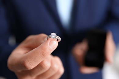 Photo of Making proposal. Man with engagement ring indoors, closeup