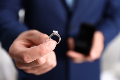 Photo of Making proposal. Man with engagement ring indoors, closeup