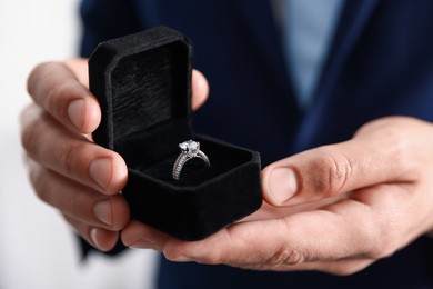 Photo of Making proposal. Man with engagement ring indoors, closeup