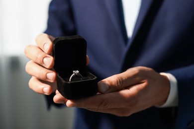 Photo of Making proposal. Man with engagement ring indoors, closeup