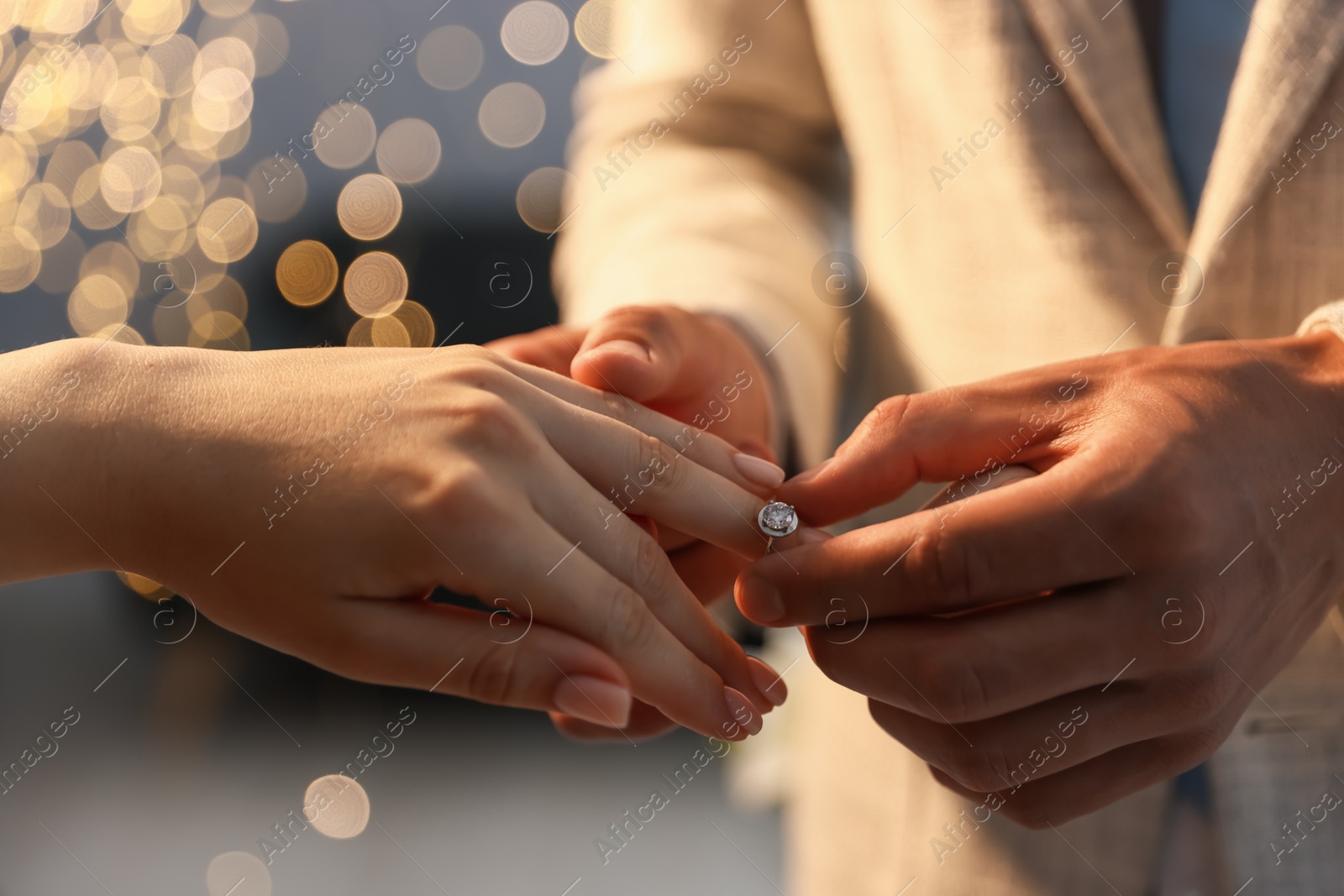 Making proposal. Man putting engagement ring on his girlfriend's finger indoors, closeup. Bokeh effect Photo of Making proposal. Man putting engagement ring on his girlfriend's finger indoors, closeup. Bokeh effect