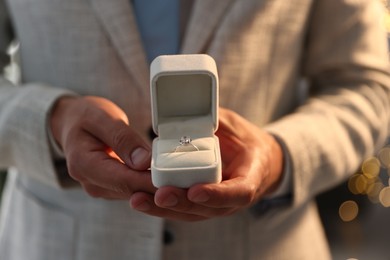 Photo of Making proposal. Man with engagement ring indoors, closeup. Bokeh effect