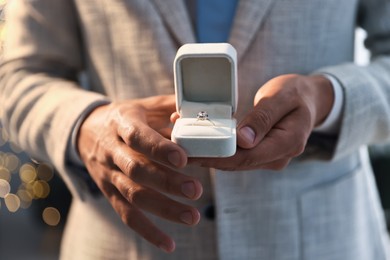 Photo of Making proposal. Man with engagement ring indoors, closeup. Bokeh effect