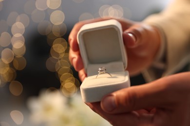 Photo of Making proposal. Man with engagement ring indoors, closeup. Bokeh effect